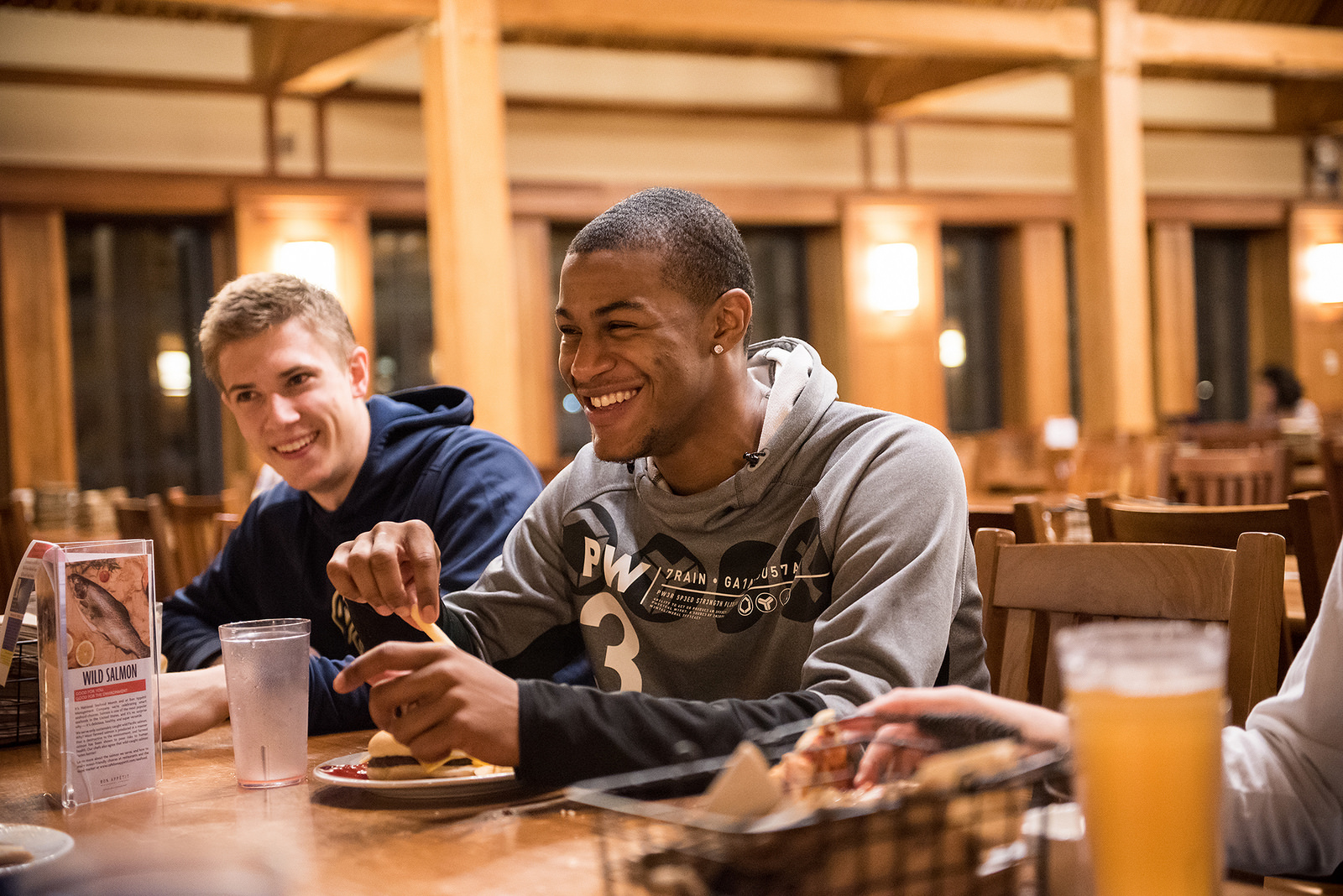 Two students laughing as they enjoy their meal in the great room.