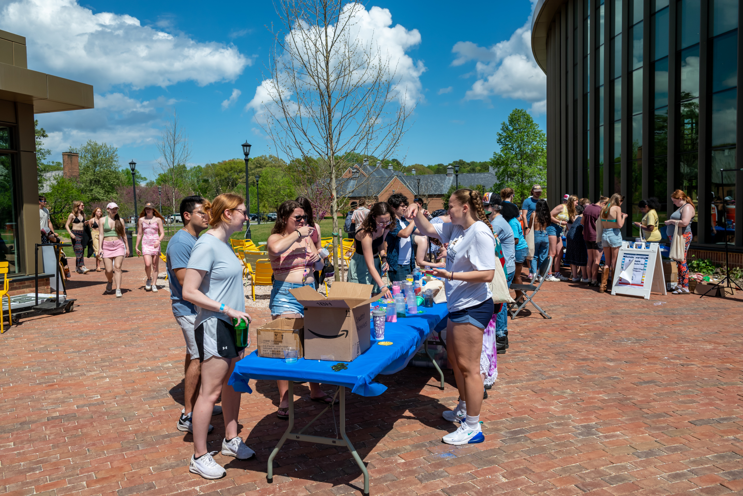 A large public event with lots of college students having conversations and bonding together on a nice sunny afternoon.