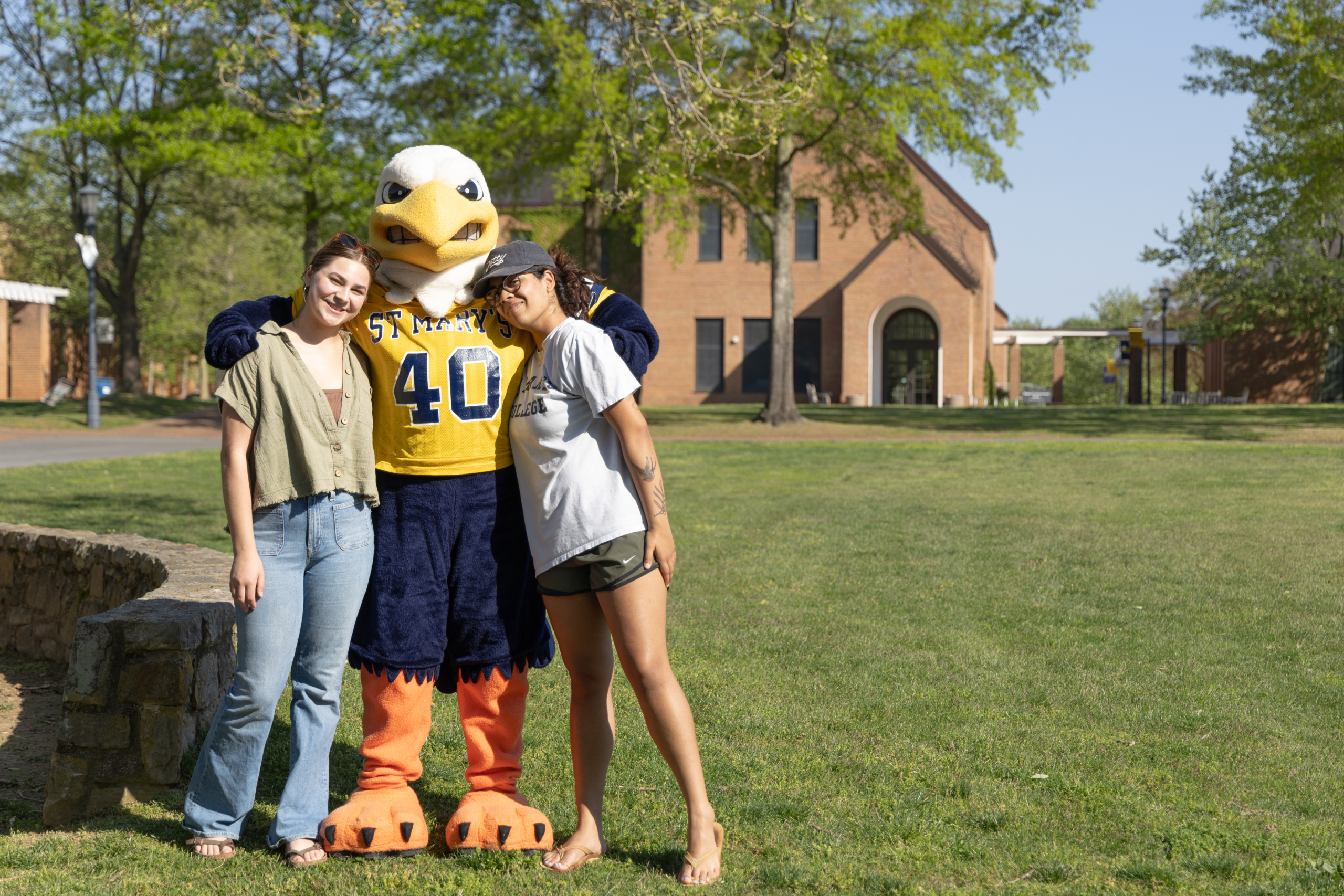 Two students taking a picture with the SMCM mascot on a nice sunny day.