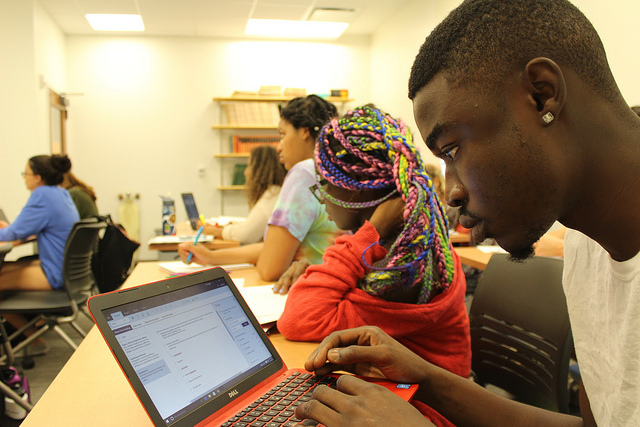 several students in a computer science class with one student working on a laptop